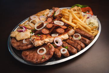 several types of roasted meat served on an oval, Serbian dish 