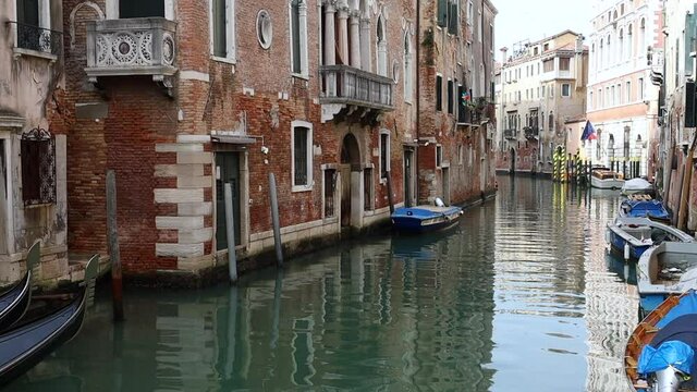 Static camera on one of the many canals of Venice in a day of high tide. Nobody in the deserted canal, water flickering in its gentle flow. 