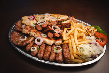 several types of roasted meat served on an oval, Serbian dish 