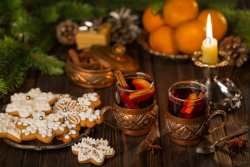 Glasses of mulled wine with cinnamon, tangerines and gingerbread on a background of candles, lights. Christmas, New Year's  idea, concept
