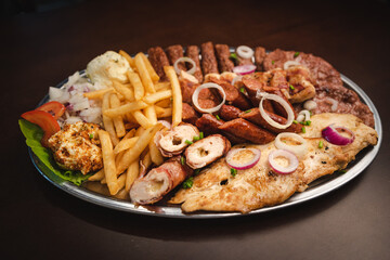 several types of roasted meat served on an oval, Serbian dish 