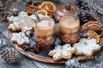 Copper cups of hot coffee with cream, cinnamon, anise and gingerbread on a copper tray. Christmas food concept in vintage style.