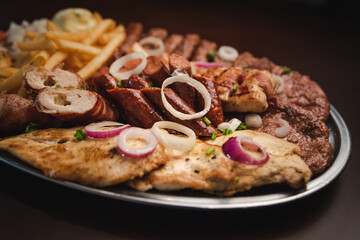 several types of roasted meat served on an oval, Serbian dish 