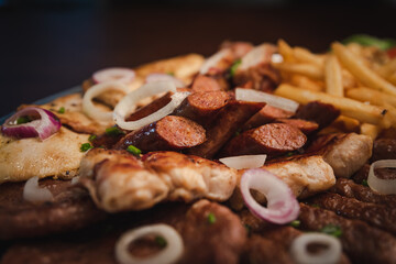 several types of roasted meat served on an oval, Serbian dish 