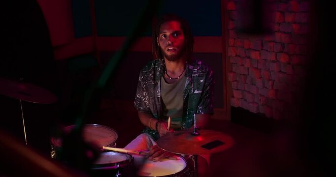 Drummer playing drums looking at singer in music studio