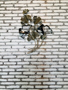 wall decoration in the form of leaf stalks made of iron. iron leaf stalk black and gold, on a white brick background.