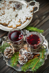 Two glasses of mulled wine in cup holders, with cinnamon and anise on a wooden background with fir branches and gingerbread. Winter Christmas still life, vintage style postcard. Soft focus.