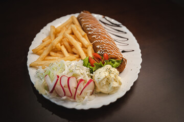 fried roll of meat with cheese with french fries and salad and onion on a plate, Serbian dish 