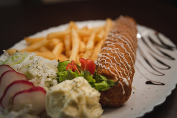 fried roll of meat with cheese with french fries and salad and onion on a plate, Serbian dish 