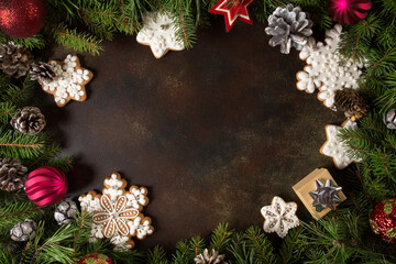 Christmas background texture - branches of spruce with pine cones, red ball and gingerbread snowflakes. Festive idea, concept in the form of a frame.