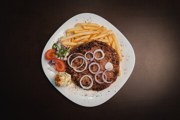 baked barbecue with french fries and salad and onion on a plate, Serbian dish 
