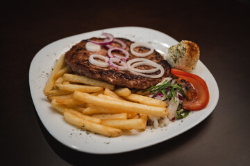 baked barbecue with french fries and salad and onion on a plate, Serbian dish 