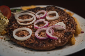baked barbecue with french fries and salad and onion on a plate, Serbian dish 
