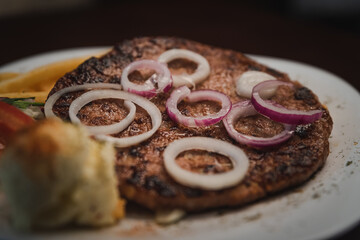 baked barbecue with french fries and salad and onion on a plate, Serbian dish 