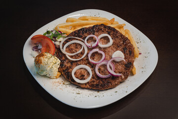 baked barbecue with french fries and salad and onion on a plate, Serbian dish 