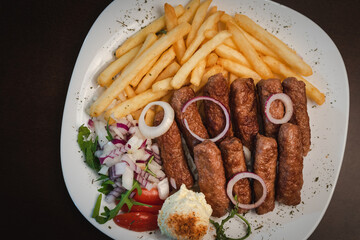 peceni rostilj sa pomfitom i salatom na tanjiru, srpsko jelo 