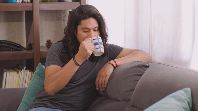 chico hispano latino bien parecido est&aacute; en casa bebiendo  algo caliente  y mira hacia  la ventana en este qu&eacute;date en casa cor la emergencia sanitria