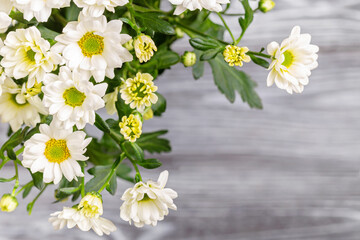 A bouquet of white bush chrysanthemums on a wooden table.