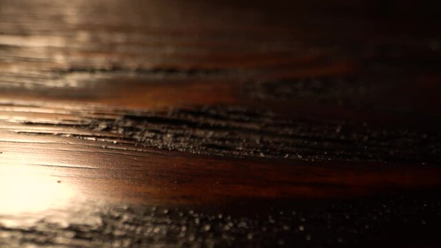 Macro flat wooden surface tracking. Vertical sliding camera moving along a brown textured table with a shiny lacquered surface. Wood texture. Dolly shot.