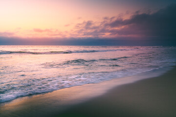 Tropical beach sunset tranquil abstract seascape with beautiful cloudy sky in yellow and pink colors on background