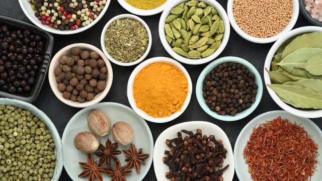 Assortment of aromatic spices and herbs in small bowls rotating