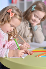 Portrait of two cute little girls drawing with pencils
