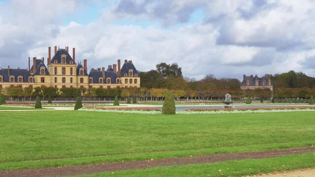 Camera Pan over Fontainebleau French Garden (Grand Parterre by Le Notre) with the royal castle in the background. Shot in autumn on a cloudy day - Fontainebleau, France