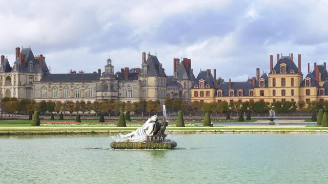 Camera Pan over Fontainebleau French Garden and the royal castle with Romulus pond in the foreground. Shot in autumn on a cloudy day - Fontainebleau, France