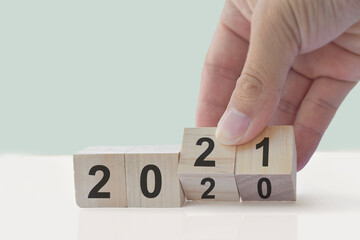 Happy New Year concept. Hand flip wooden cubes 2020 change to 2021 on white table.