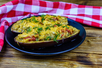 Plate with baked stuffed eggplants on a wooden table