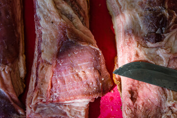 Raw piece of pork belly and knife on a cutting board