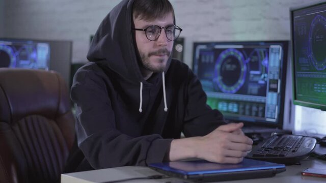 Confident thoughtful young hacker closing laptop and sighing. Portrait of worried Caucasian man in eyeglasses and hoodie hacking online web site and unplugging USB device. Virtual security.