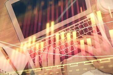 Double exposure of man's hands typing over computer keyboard and forex graph hologram drawing. Top view. Financial markets concept.