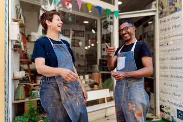 Cheerful coworkers talking while standing outside ceramic shop