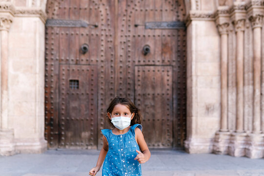 Girl wearing mask running in front of historic door