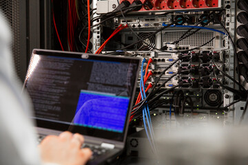 Close-up of male IT professional using laptop in server room
