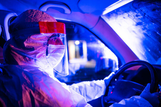 Mid Adult Man Wearing Protective Suit Driving Ambulance At Night