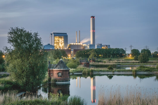 Germany, Hamburg, Pump house of former waterworks on Elbe island Kaltehofe with Tiefstack power plant in background at dusk