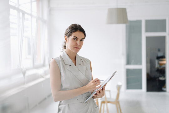 Businesswoman holding notepad while standing at office