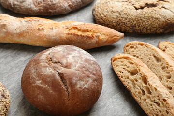 Different kinds of fresh bread on grey table