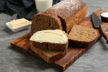Fototapeta na wymiar Tasty freshly baked bread with butter on grey table
