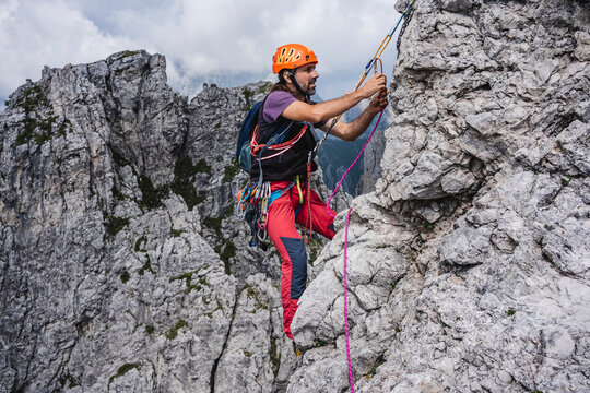 Male mountaineer with rope climbing on mountain, European Alps, Lecco, Italy