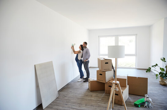Couple trying light fixture on wall at new home
