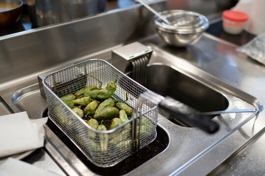 Padr&radic;&ge;n peppers in basket on deep fryer at commercial kitchen