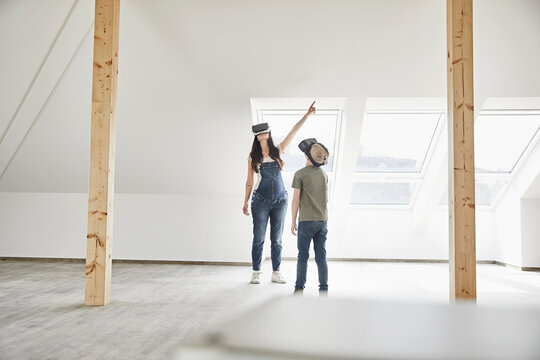 Mother and son wearing virtual reality simulator while standing in domestic room