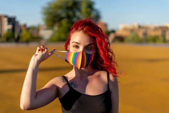 Redhead woman wearing multi colored face mask on sunny day