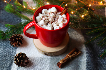 Christmas hot drinks. Hot cocoa in a red mug with marshmallows and cinnamon on a festive Christmas background. Close-up, selective focus