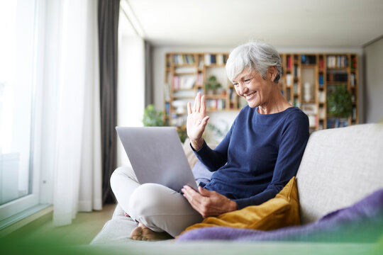 Senior Woman Doing High Five On Video Call While Using Laptop At Home