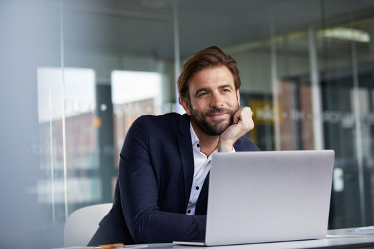 Businessman with head in hands leaning on desk while sitting in office