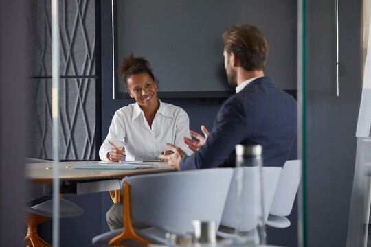 Businessman and colleague discussing while sitting in office